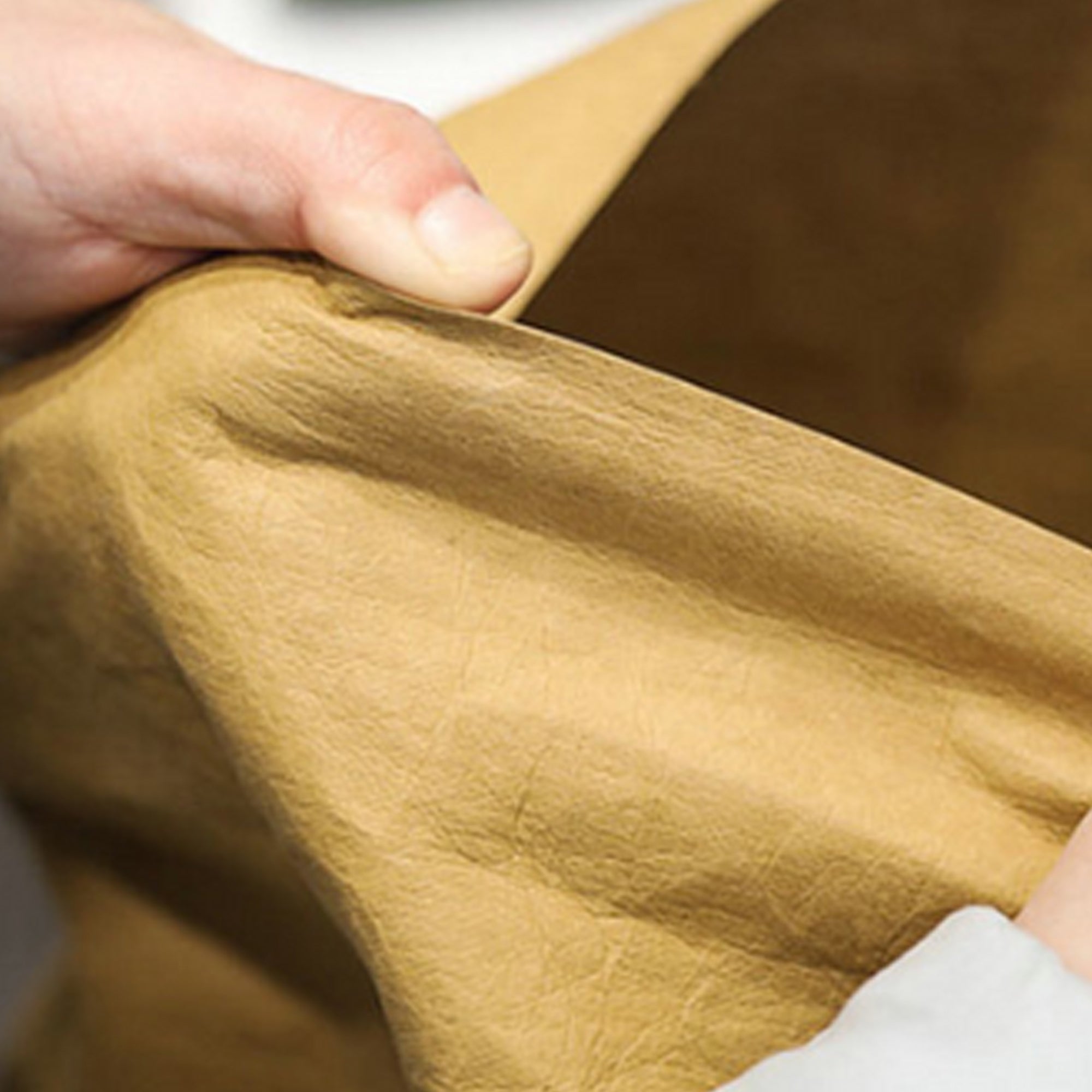 German Kraft paper material being stretched in someone's hands, showcasing its durability, flexibility, and eco-friendly qualities.