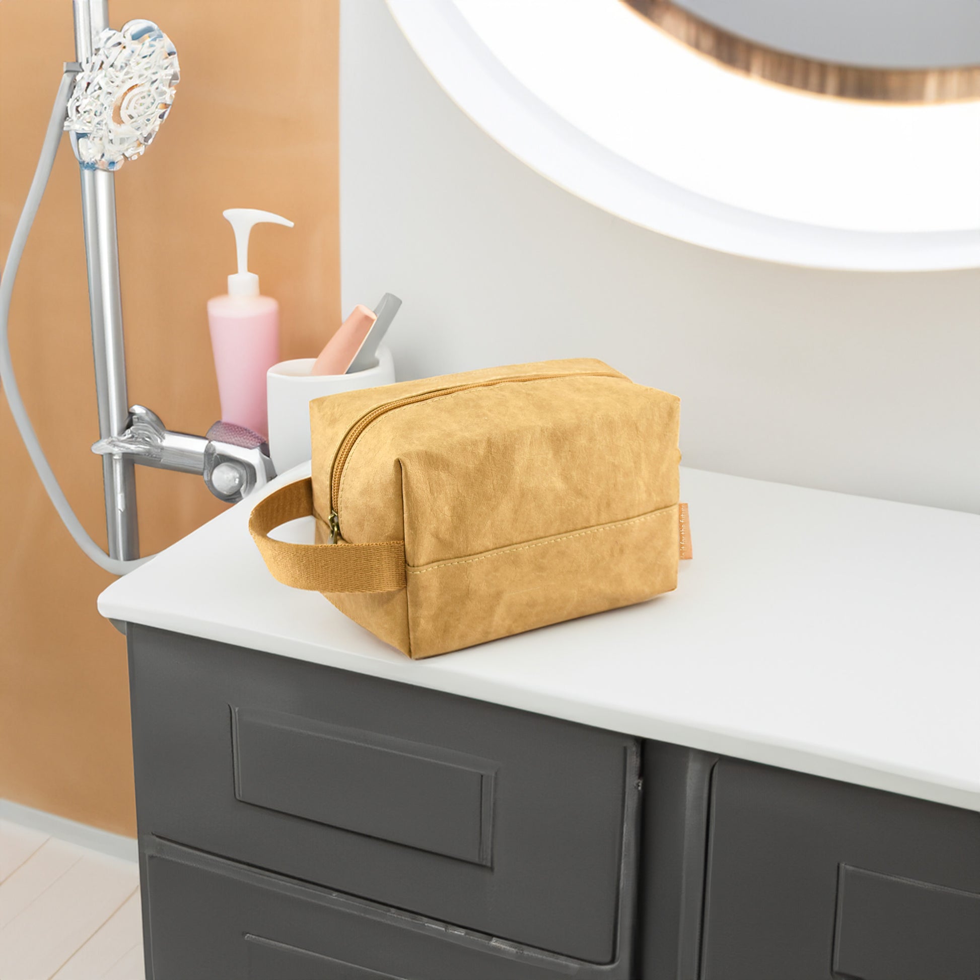 Munro Kraft Paper Cosmetic Bag placed on a bathroom bench with shower supplies in the background, showcasing its eco-friendly, durable design and spacious interior for organizing toiletries.