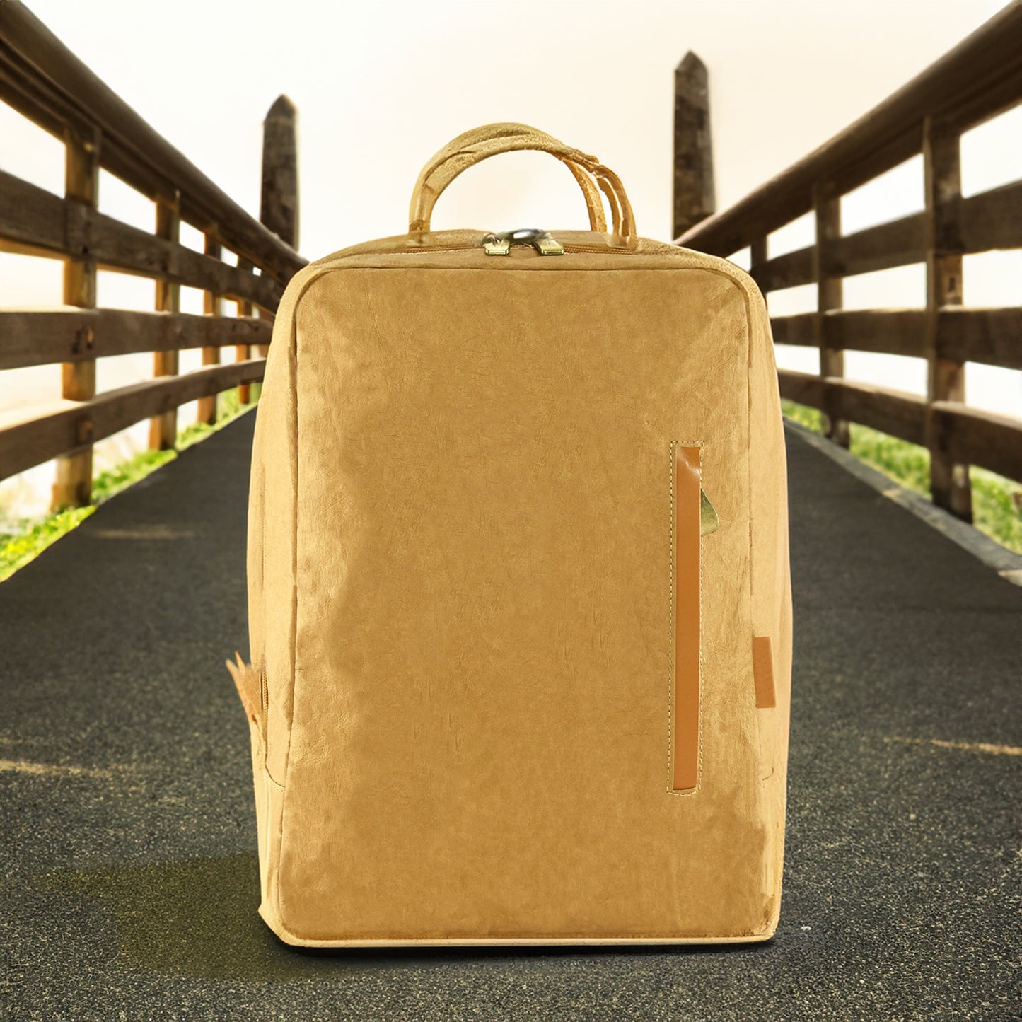 Suna Kraft Paper Laptop Backpack shown on a road with brown fencing on each side, highlighting its rugged yet eco-friendly design for outdoor adventures.