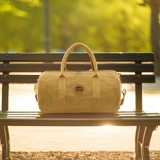 Jakob Kraft Paper Duffle Bag resting on a park bench with a sunny afternoon background, highlighting the eco-friendly, durable design of the bag perfect for travel or gym use.