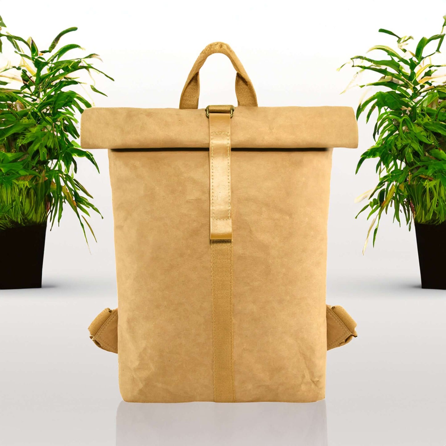 The Mate Kraft Paper Backpack placed on a white floor with two potted plants behind it, showcasing its eco-friendly design and versatility for everyday use.